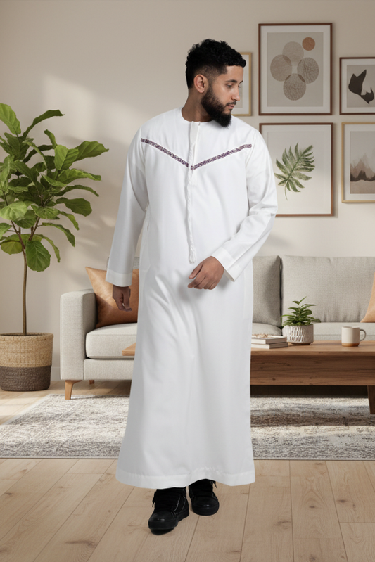 Man in a white robe standing in a modern living room with plants and a sofa.